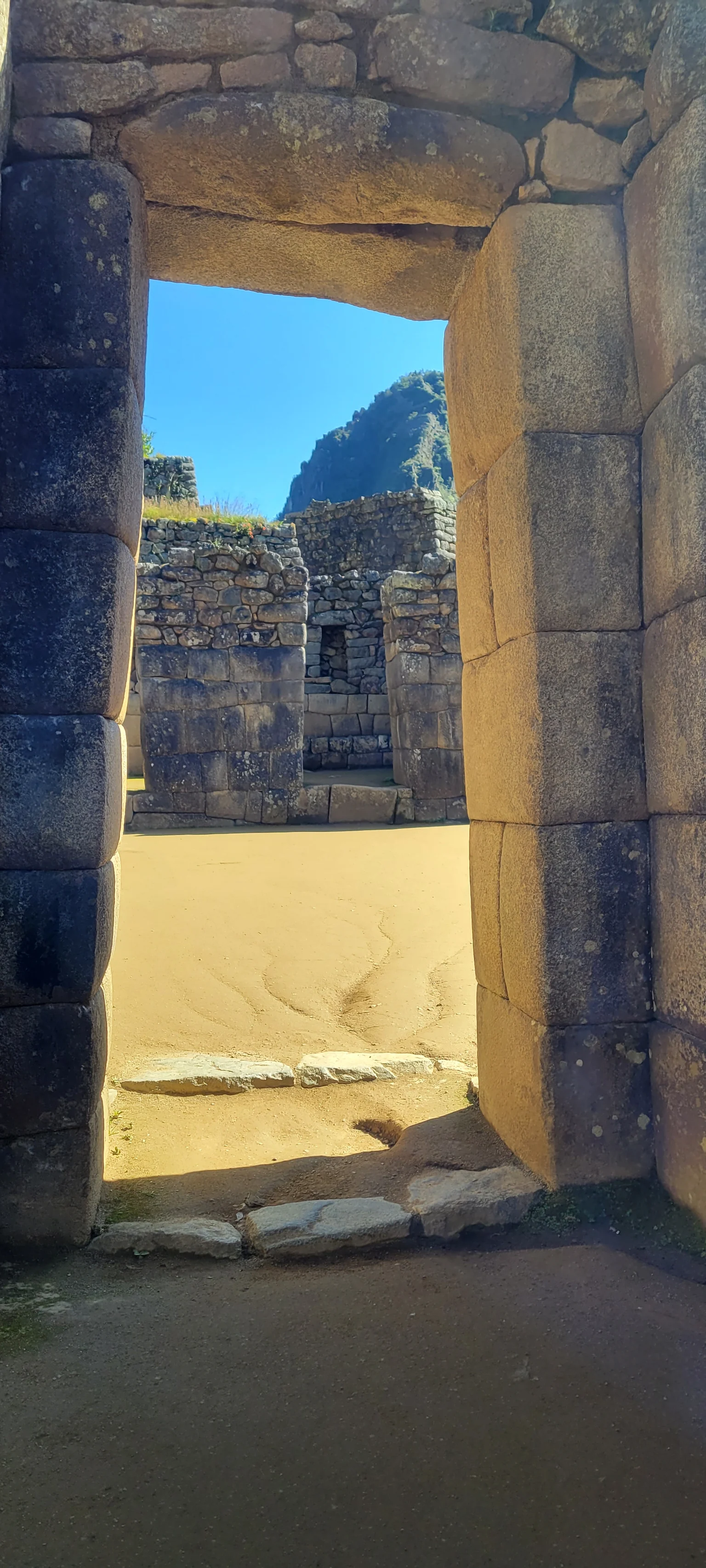 Passagem de pedra em Machu Picchu: pela porta, a luz do dia e as montanhas do outro lado.